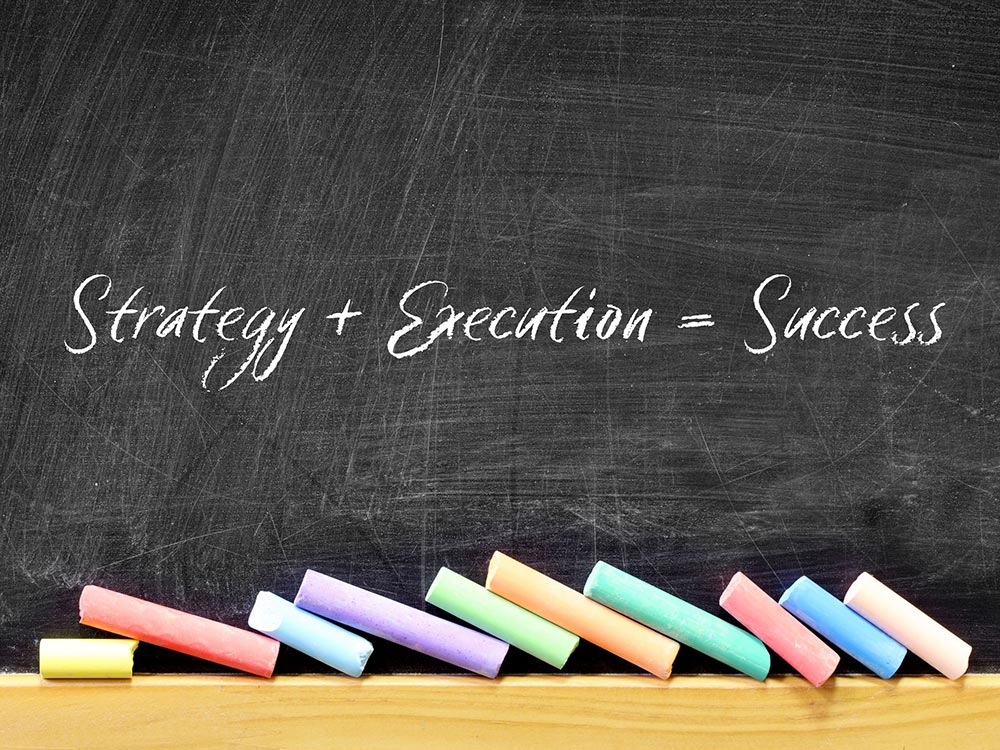 Strategy plus execution equals success written on blackboard with colourful chalk below